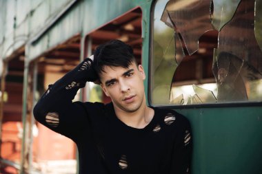 Terk edilmiş binanın yanındaki genç adamın portresi