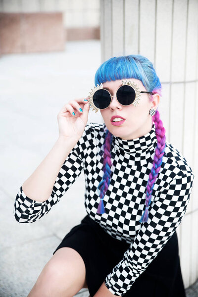 Portrait of beautiful young woman with blue hair wearing sunglasses