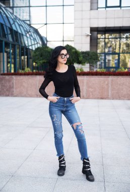 Genç ve güzel bir kadın şehirde poz veriyor. 