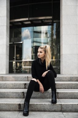 Basamaklarında oturan genç güzel kadın 