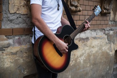 Genç yakışıklı adam şehirde gitar çalıyor.  