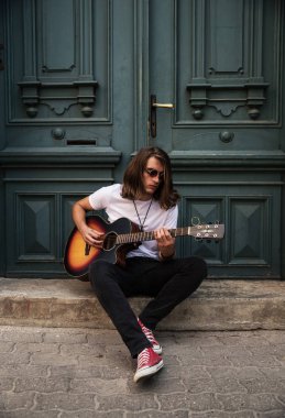 Genç yakışıklı adam şehirde gitar çalıyor.  