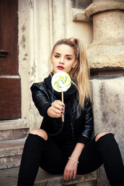 Young beautiful woman with lollipop in city