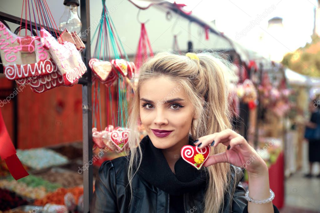 Young beautiful woman with candy in form of heart 