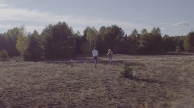 Hava kız ormanın alan takip adam çekim. Kadın peşinde adam çekim hava çim alan ve onlar çam ormanına azalıyor