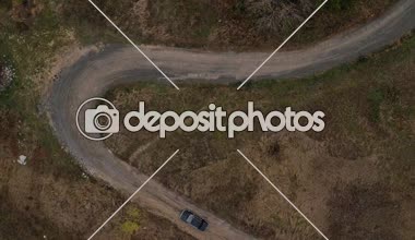 Hava üstten görünüm bir araba ile sıkı virajlı küçük yolda gidiyor. Havadan görünümü eski siyah bmw sıkı kıvrımları ile ülke yolda gidiyor