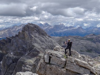 Uzun yürüyüşe çıkan kimse kayanın üzerinde duruyor. Mesafe içine bakar güzel alp kayalar.