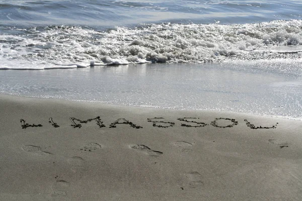 単語リマソール暗い湿った砂に書かれている 靴の跡 リマソール キプロス Dasoudi ビーチで泡波 — ストック写真