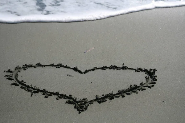 Forma Coração Desenhado Areia Escura Molhada Com Uma Onda Espumosa — Fotografia de Stock