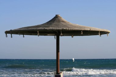 İp plaj şemsiyesi bulutsuz mavi gökyüzü ve denizin dalgalı önünde