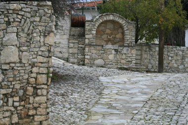 Kıbrıs köy eski bir taş su çeşme ile dar Arnavut kaldırımlı sokakta 