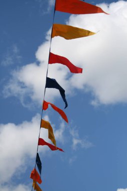 Çok renkli kumaş mavi gökyüzü ve beyaz bulutlar önünde rüzgarda sallayarak bir ipte flamalar