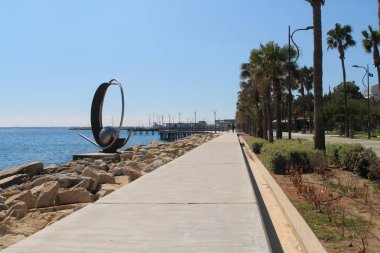 Limasol, Kıbrıs, 8 Mart 2019: Bir heykel ve yürüyen insanlarla Molos mesire görünümünü