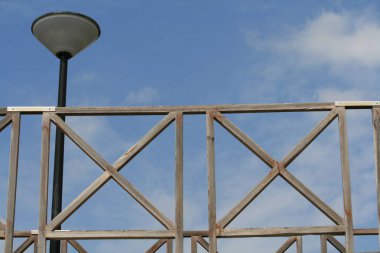 Mavi gökyüzü ve beyaz bulutlar önünde bir sokak lambası ile ahşap yaya köprüsü parçası