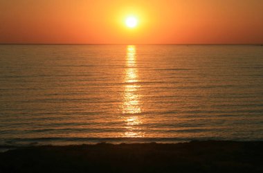 Akdeniz üzerinde parlak turuncu günbatımı; Kissonerga Köyü sahilinde, Kıbrıs görüntülemek 
