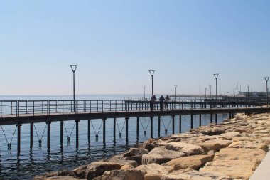 Limasol, Kıbrıs, 22 Mart, 2019: güneşli bir günde metal korkuluk, sokak lambaları ve üç ayakta erkek ile Molos Promenade üzerinde Seaside yolu 