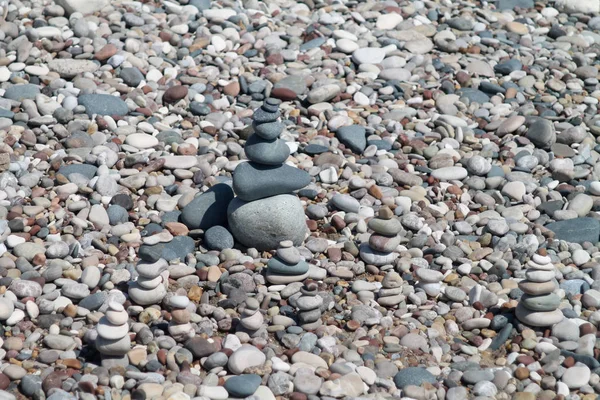 シングルビーチの小石の中でいくつかの異なる禅石のピラミッドのクローズアップ — ストック写真