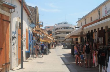 Limasol, Kıbrıs, 12 Nisan 2019: Eski kentte küçük hediyelik eşya dükkanları ve güneşli bir günde yürüyen ya da ayakta duran insanların olduğu turistik sokak