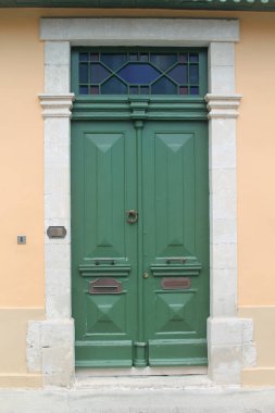 Yeşil ahşap vintage ön kapı yukarıda bir vitray pencere ve ilginç bir metal kapı tokamı ile 