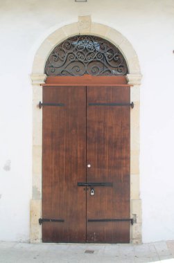 Beyaz bir taş duvar da bir taş kemer ve metal ızgaralar ile eski moda kahverengi ahşap ön kapı 