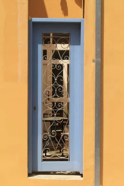 Wąskie Zewnętrzne Niebieskie Drewniane Drzwi Kratami Metalowymi Żółtym Kamiennym Ścianie — Zdjęcie stockowe