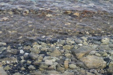 Dalgalı şeffaf deniz suyunun altında farklı şekiller, Boyutlar ve renklerin taş ve çakıl yakın çekim