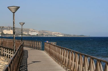 Açık mavi gökyüzü panoramik manzaralı Limasol sahilindeki tahta köprü, Akdeniz ve güneşli bir yaz gününde bir kıyı şeridi.