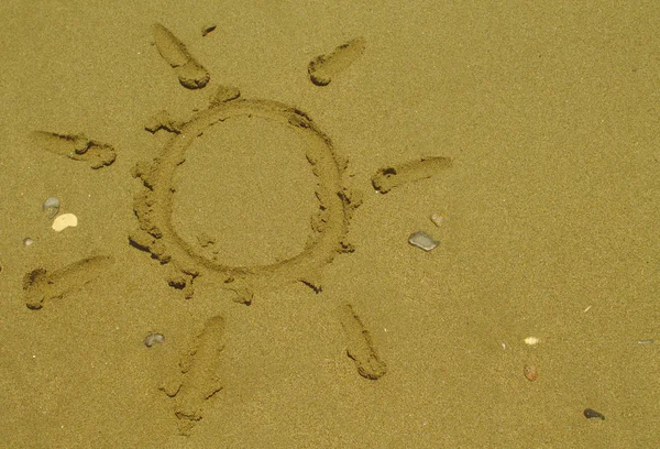 Kıbrıs'ta yaz güneşli plajda birkaç çakıl ile ıslak sarı kum üzerinde çizim Güneş şekli 