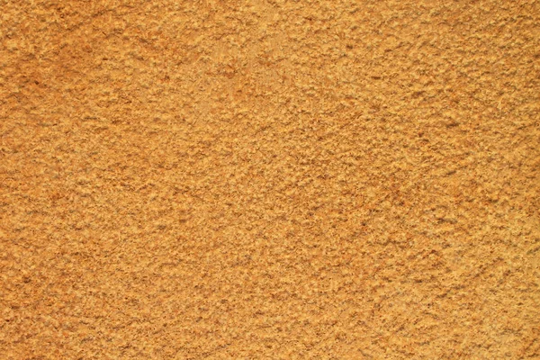 Surface of a rough textured yellow stone wall
