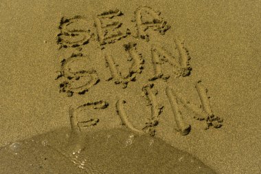 Kelime deniz, Güneş, eğlenceli yaz plajında şeffaf dalgalı deniz suyu yakın ıslak sarı kum üzerine yazılmış