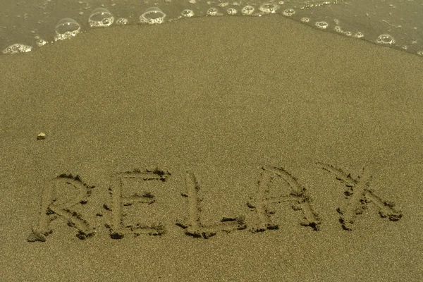 Parola Relax Scritta Sulla Sabbia Gialla Bagnata Fronte All Acqua — Foto Stock