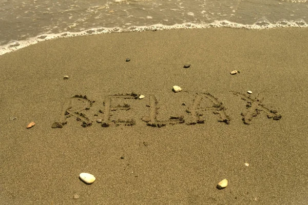 夏天海滩的海水前 在潮湿的黄沙滩上写上几块鹅卵石的 这个词 — 图库照片