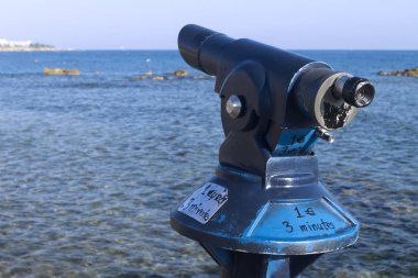 Güneşli bir yaz gününde Baf sahilinde Akdeniz'in önünde bozuk para yla çalışan bir turist teleskobunun yakın çekim