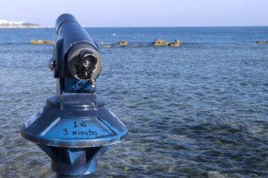 Güneşli bir yaz gününde Baf sahilinde Akdeniz'in önünde bozuk para yla çalışan bir turist teleskobunun yakın çekim