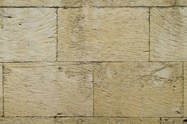 Kare şekilli doğal taş bloklardan bej bir duvarın parçası