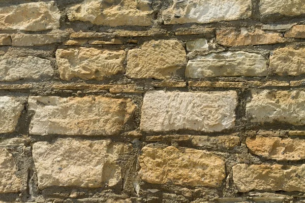 Part of an exterior brick wall from the beige natural stones with cement