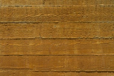 Güneş ışığında yatay kaba sarı ahşap plakalar bir çit parçası