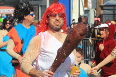 Limasol, Kıbrıs, 10 Mart 2019: Bir elinde kulüp, diğer elinde bir aylak bira ile mağara adamı karnaval kostümü giymiş adam Yıllık Limasol Karnaval Festivali'nin Büyük Geçit Töreni'ne katılıyor 