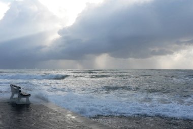 Dalgalı dalgalar ve deniz kenarında bulutlu bir günde koyu gri bulutlu gökyüzü ile Fırtınalı deniz