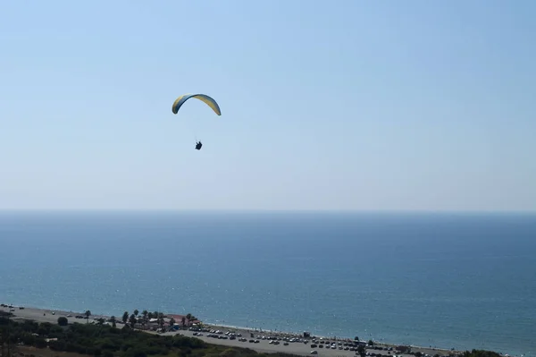 Kolorowy Paralotniarz Lecący Jasnoniebieskim Niebie Nad Brzegiem Morza Horyzontem Mgły — Zdjęcie stockowe