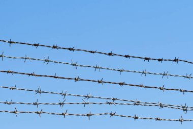 Açık mavi gökyüzünün önündeki dikenli tellere yakın çekim