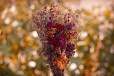 Turuncu yeşil arka planda çok renkli kurutulmuş bitki ve çiçek buketi.