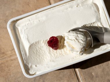 Bir kepçe vanilyalı dondurma ve gün ışığında ahududu.