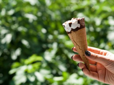 Dondurma külahı güneş ışığında bulanık yeşil arka planda. 