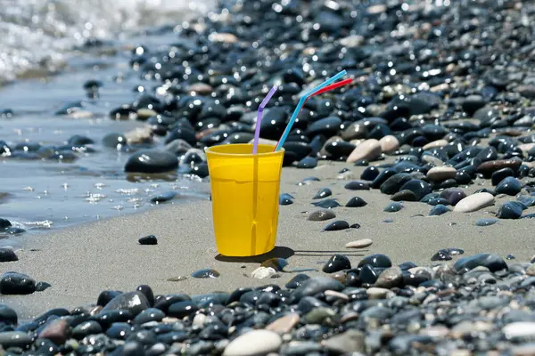 Gelbes Trinkglas Mit Bunten Strohhalmen Meeresstrand Neben Glitzernden Kieselsteinen — Stockfoto