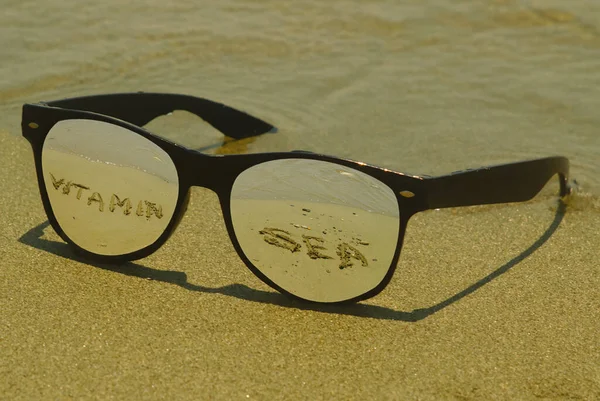 Γυαλιά Ηλίου Αντανάκλαση Των Λέξεων Βιταμίνη Θάλασσα Υγρή Άμμο Στην — Φωτογραφία Αρχείου