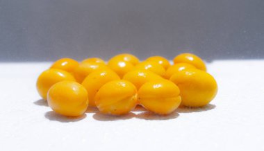 Yağmur damlalarının altında beyaz bir arkaplanda kayısılar