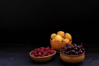 Siyah arka planda kiraz, kayısı, ahududu.