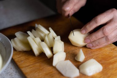 Kesme tahtasında patates dilimlemek.