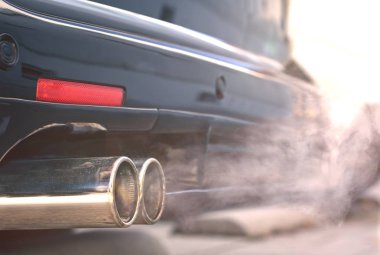Close up of smoky dual exhaust pipes from a starting diesel car. clipart